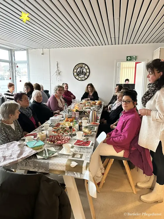 Das Team des Barßeler Pflegedienstes beim gemeinsamen Frühstück an einer langen Tafel
